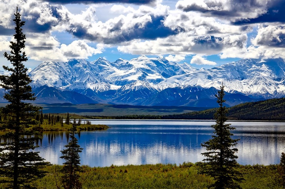 Denali National Park with blue skies, snow capped mountains and calm glacier lake