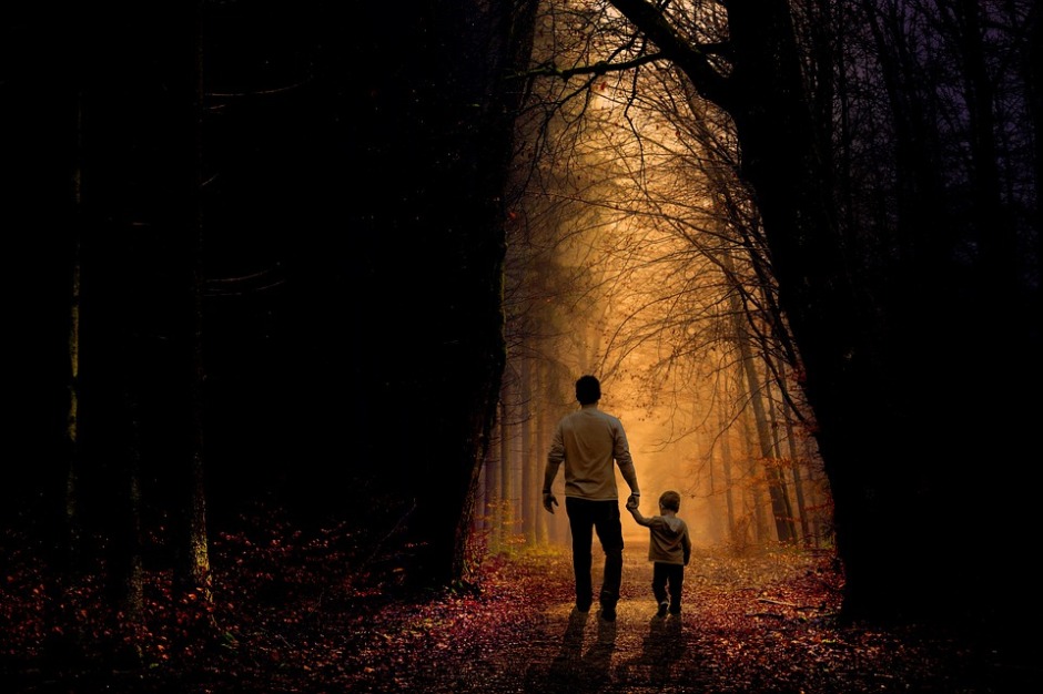 father walking with young son and holding hands walking on a path