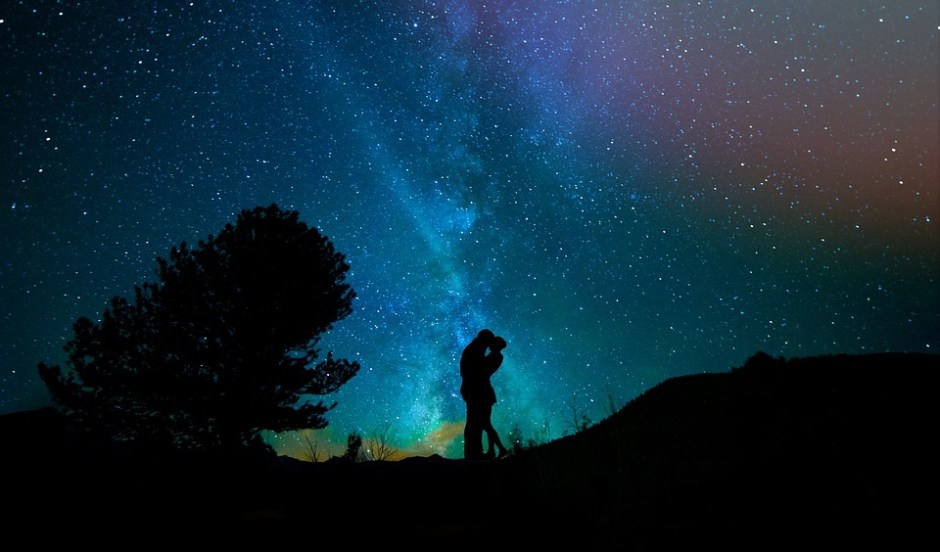 humans embrace with the starry night sky behind them