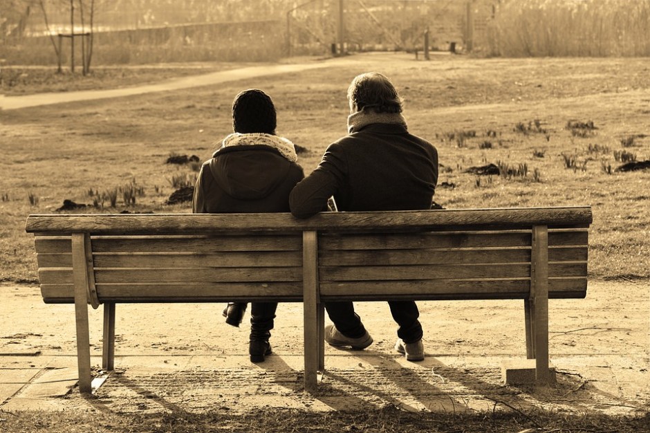 See the backs of two people sitting on a bench