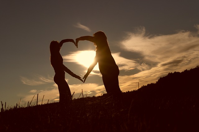two silhouettes making a heart shape over the skyline