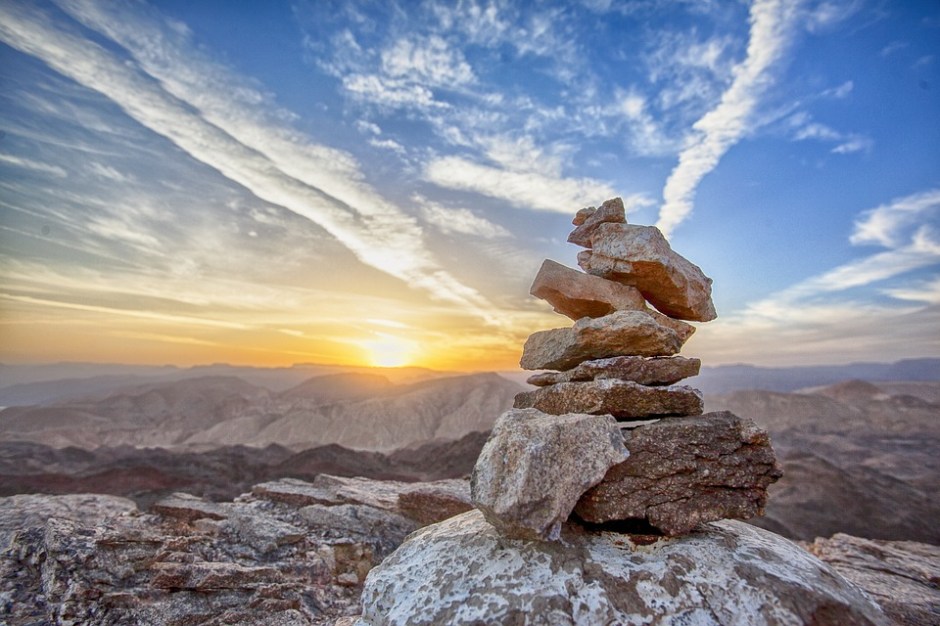 a stone cairn with mountains and sunrise in the background